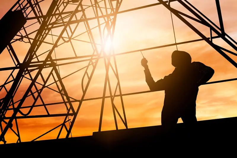 A line worker on a steel tower at sunset